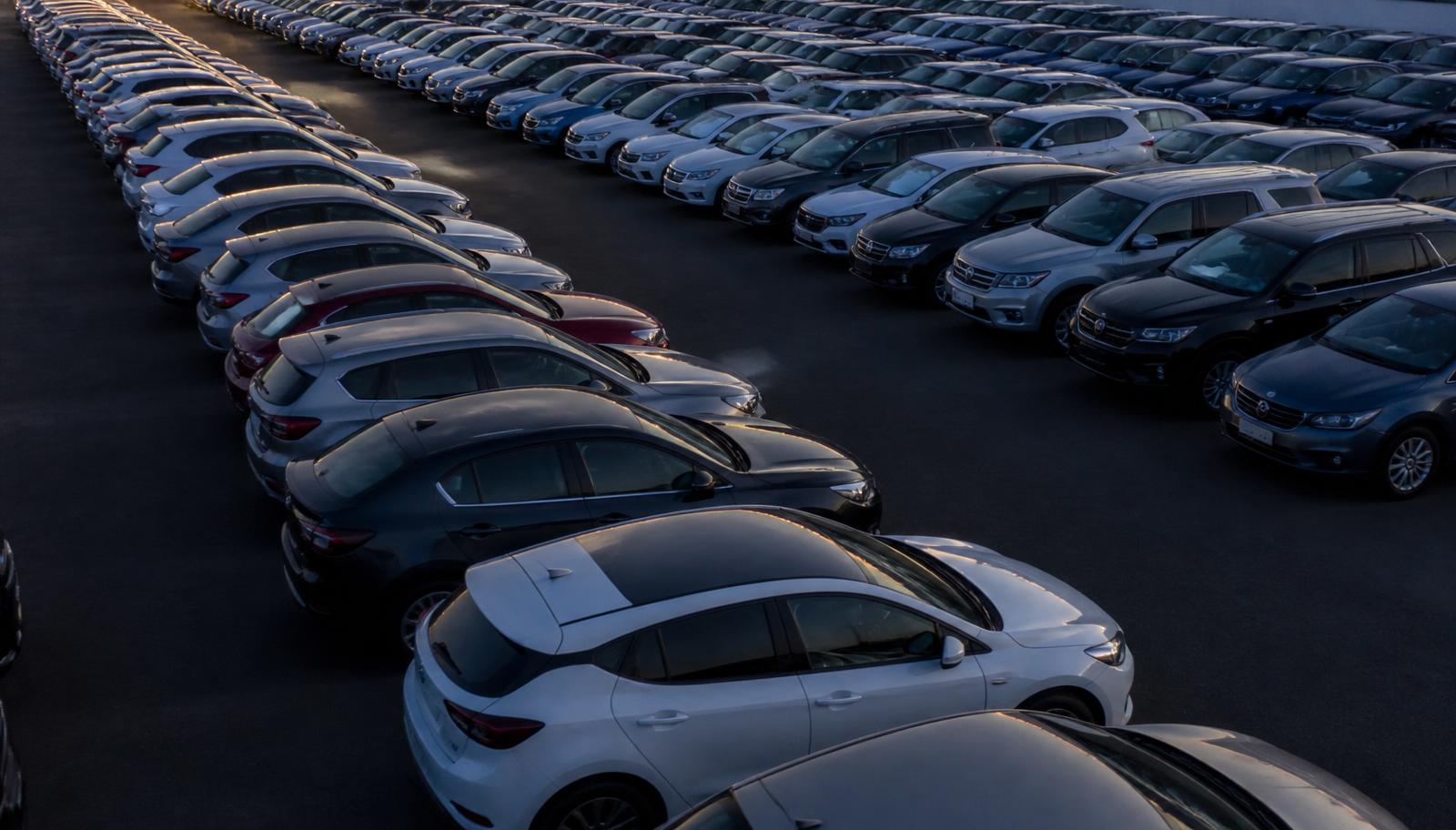 Rows of used cars parked in an Australian auction yard at dusk